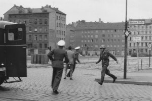 „Sprung in die Freiheit“, Bernauer Straße, 15. August 1961: Der DDR-Grenzpolizist Conrad Schumann rennt nach seinem Sprung zu einem Streifenwagen der West-Berliner Polizei. Zwei Beamte bergen seine Waffe