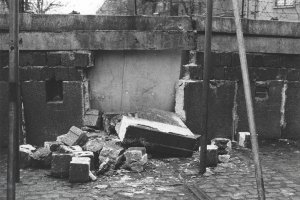 Aus der Hohlblockstein-Mauer sind große Stücke herausgebrochen und liegen auf dem Straßenpflaster davor. Das Loch ist rückseitig mit Platten verschlossen.