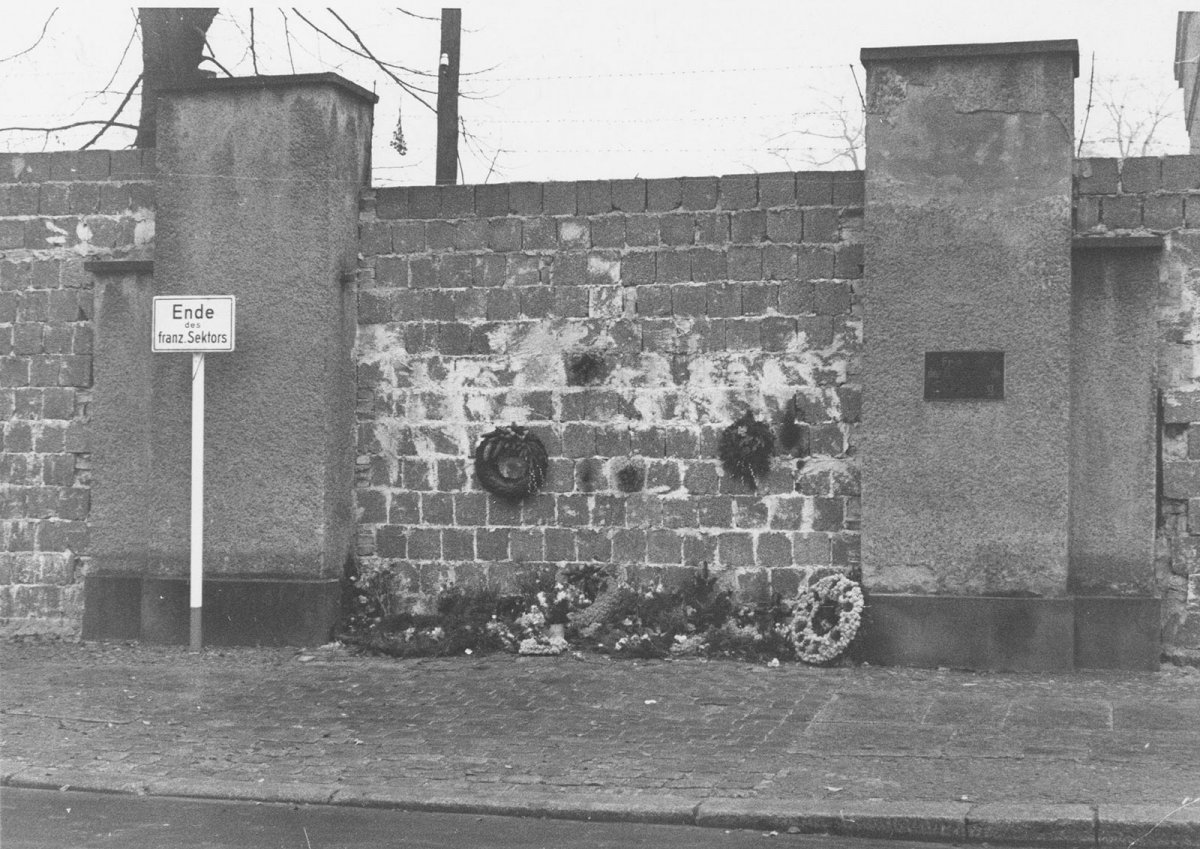 West-Berliner, die den St.-Hedwigs-Friedhof an der Liesenstraße nicht mehr betreten dürfen, legen ihren Grabschmuck am zugemauerten Friedhofseingang ab, 26. November 1961.