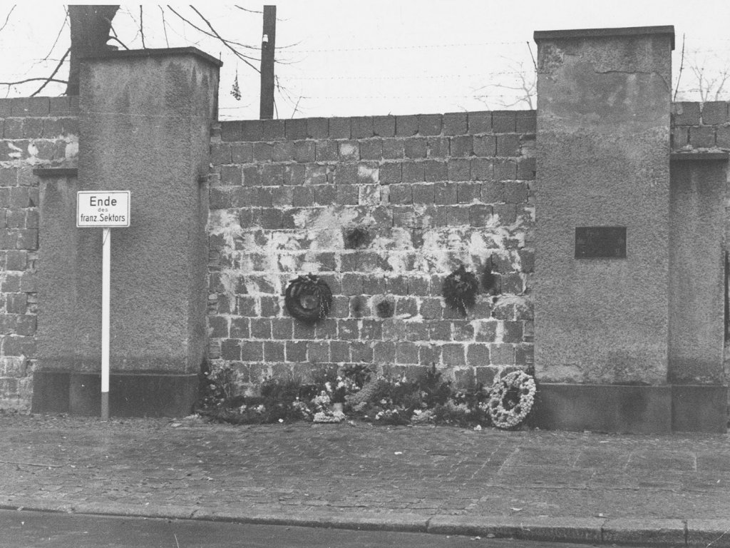 West-Berliner, die den St.-Hedwigs-Friedhof an der Liesenstraße nicht mehr betreten dürfen, legen ihren Grabschmuck am zugemauerten Friedhofseingang ab, 26. November 1961.