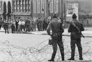 Stacheldrahtsperre in der Bernauer Straße: Volkspolizisten halten Ost-Berliner in Schach; Aufnahme 13. August 1961