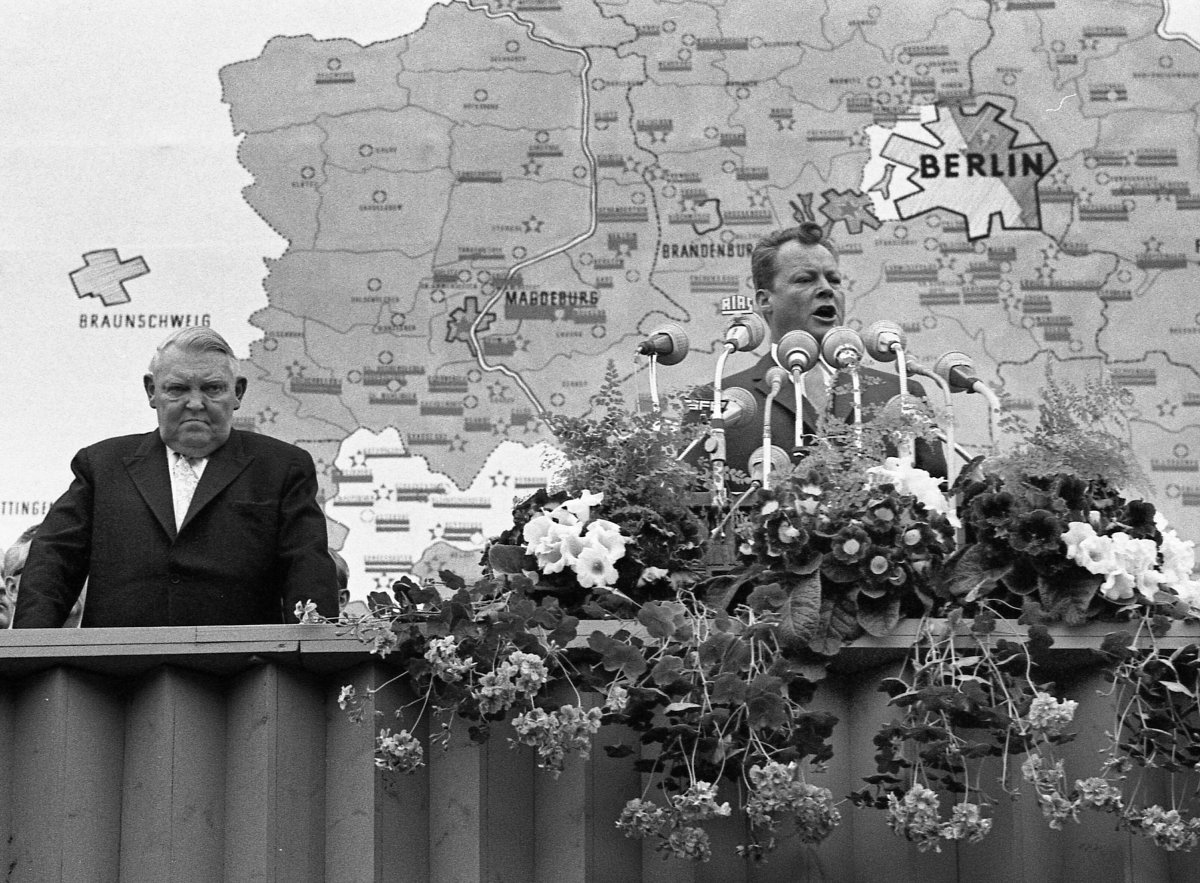 1962: Berlins Regierender B&uuml;rgermeister Willy Brandt spricht am ersten Jahrestag des Mauerbaus vor dem Sch&ouml;neberger Rathaus. In diesen 12 Monaten ist klar geworden, dass die Grenzabriegelung permanent ist. Brandt spricht von der &bdquo;objektiven Niederlage eines Regimes, das seine Leute einmauern musste, damit es nicht ein Regime ohne Volk wurde&ldquo;.