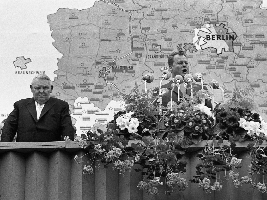 1962: Berlins Regierender Bürgermeister Willy Brandt spricht am ersten Jahrestag des Mauerbaus vor dem Schöneberger Rathaus. In diesen 12 Monaten ist klar geworden, dass die Grenzabriegelung permanent ist. Brandt spricht von der „objektiven Niederlage eines Regimes, das seine Leute einmauern musste, damit es nicht ein Regime ohne Volk wurde“.