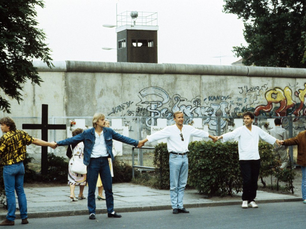 1986: Am 9. August zum 25. Jahrestag des Mauerbaus bilden in West-Berlin tausende Bürgerinnen und Bürger aus Protest gegen die Mauer eine Menschenkette zwischen der Bernauer Straße und dem Checkpoint Charlie. Im Hintergrund sind die weißen Kreuze zu sehen, mit denen in West-Berlin an die Todesopfer gedacht wird.