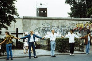 1986: Am 9. August zum 25. Jahrestag des Mauerbaus bilden in West-Berlin tausende B&uuml;rgerinnen und B&uuml;rger aus Protest gegen die Mauer eine Menschenkette zwischen der Bernauer Stra&szlig;e und dem Checkpoint Charlie. Im Hintergrund sind die wei&szlig;en Kreuze zu sehen, mit denen in West-Berlin an die Todesopfer gedacht wird.