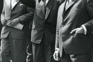 Willy Brandt geht rechts im Vordergrund eine Treppe hinunter. Neben ihm wirft Adenauer den Arm gestikulierend in die Luft. Daneben und dahinter gehen weitere Männer.