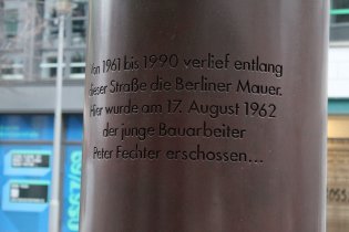 Nahaufnahme des Textes auf der Rückseite der Säule: Von 1961 bis 1990 verlief entlang dieser Straße die Berliner Mauer. Hier wurde am 17. August 1962 der junge Bauarbeiter Peter Fechter erschossen…