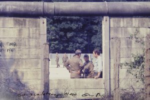 Nahaufnahme der Mauer. Im Zentrum die herausgebrochene L&uuml;cke, durch die vier Grenzsoldaten und ein Mann in Zivil zu sehen sind.