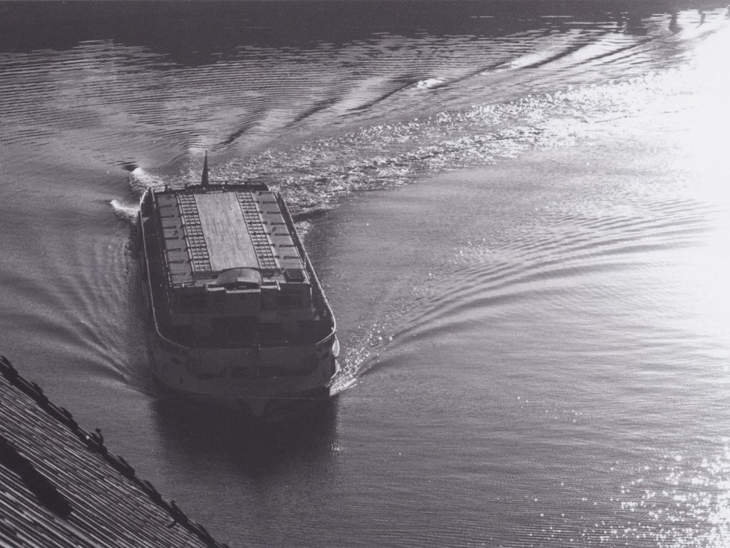 Das Schiff ist aus der Vogelperspektive aufgenommen. Die Bewegungen auf der Wasseroberfläche lassen erkennen, dass es eine scharfe Kurve genommen hat.