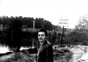 Im Vordergrund steht Hartmut Richter und blickt in die Kamera, hinter ihm steht ein Schild mit der Aufschrift: Hier endet West-Berlin. Im Hintergrund verlaufen der Kanal und die Mauer. Am anderen Ufer ist ein Wachturm zu erkennen.