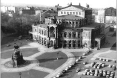 Blick auf die Dresdener Semperoper aus der Vogelperspektive. Links im Vordergrund das König-Johann-Denkmal, rechts ein Parkplatz.