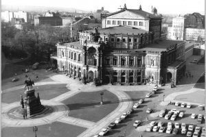 Blick auf die Dresdener Semperoper aus der Vogelperspektive. Links im Vordergrund das König-Johann-Denkmal, rechts ein Parkplatz.