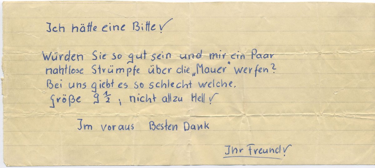 "Ich hätte eine Bitte! Würden Sie so gut sein und mir ein Paar nahtlose Strümpfe über die "Mauer" werfen? Bei uns gibt es so schlecht welche. Größe 9 1/2, nicht allzu hell! Im Voraus Besten Dank. Ihr Freund!"