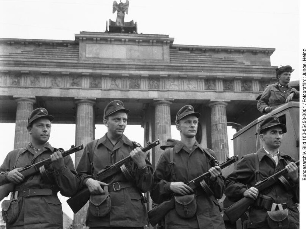 Dieses Foto vom 14. August 1961 dient der SED-Propaganda als visuelles Gegenstück zu den vom Westen verbreiteten Aufnahmen der Mauer – wie dem „Sprung in die Freiheit“ von Conrad Schumann. Die Aufnahme der vier Männer vor dem Brandenburger Tor soll den Mauerbau als Maßnahme zur „Friedenssicherung“ legitimieren. Es soll eine „menschliche Mauer“ zeigen, eine Schutz- und Verteidigungsgeste gegen den Westen.