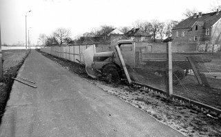 Im Bildzentrum sieht man einen LKW, der teilweise durch den Grenzzaun durchgebrochen ist. Auf dem Postenweg liegt noch die zurückgelassene Fluchtleiter.