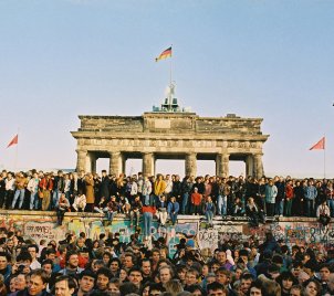 Menschenmengen drängen sich auf und vor der Mauer vor dem Brandenburger Tor.