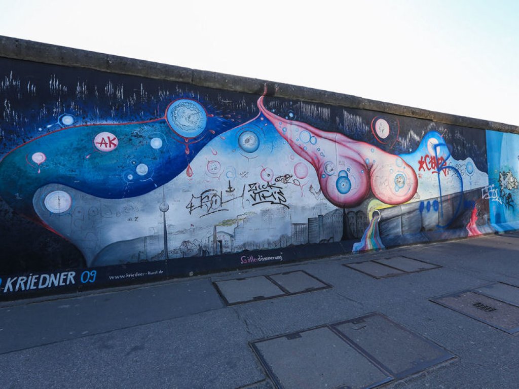 Die "East Side Gallery" als längste denkmalgeschützte Leinwand der Welt, hier exemplarisch das Werk "Götterdämmerung" von Gerald Kriedner; Aufnahme 2015 Die "East Side Gallery" als längste denkmalgeschützte Leinwand der Welt, hier exemplarisch das Werk "Götterdämmerung" von Gerald Kriedner; Aufnahme 2015