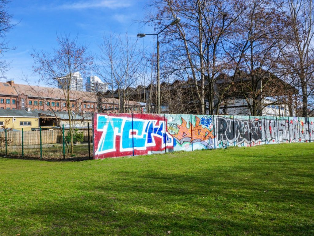 Hinterlandmauer und Lichttrasse der Vorfeldsicherung der DDR-Grenzanlagen an der Puschkinallee in Berlin-Treptow, die nach dem Mauerfall bemalt wurde (1); Aufnahme 2015