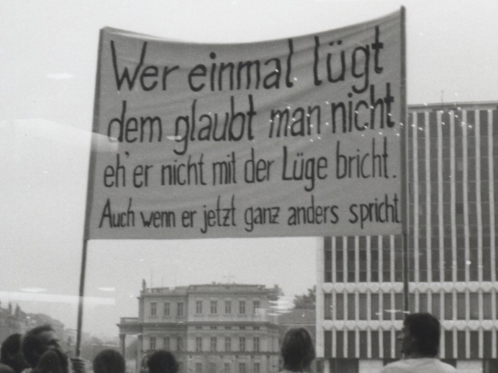 Demonstranten halten ein Transparent in die Höhe mit der Aufschrift: Wer einmal lügt dem glaubt man nicht, eh er nicht mit der Lüge bricht. Auch wenn er jetzt ganz anders spricht.
