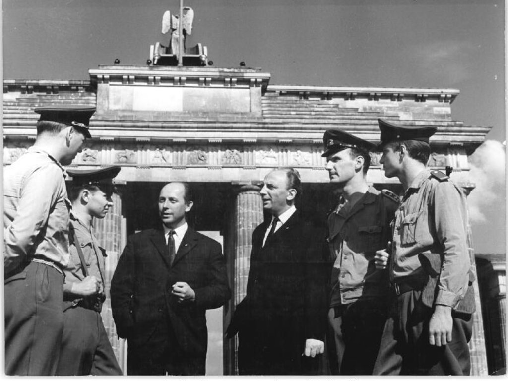 1966: Um die vermeintliche Friedfertigkeit des Mauerbaus zu betonen, inszeniert die DDR-Führung fünf Jahre später ein Wiedersehen von Paul Stiawa, Joachim Behrens, Roland Höfer und Werner Fromm. Die vier Protagonisten der Aufnahme vom 14. August 1961 posieren wieder am Brandenburger Tor.