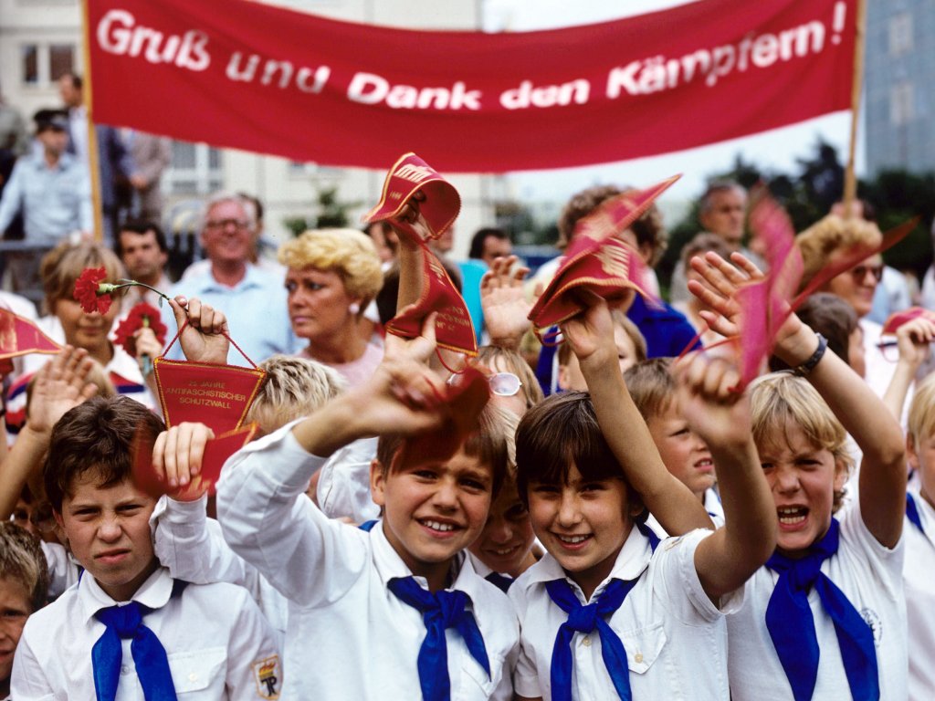 1986: Jungpioniere bei einer Pionierdemonstration zum 25. Jahrestag des „antifaschistischen Schutzwalls“. Die Kinder und Jugendlichen der staatlichen Pionierorganisation der DDR wurden flächendeckend instrumentalisiert, den Mauerbau in Liedern, Gedichten und Solidaritätsbekundungen als „friedenssichernde Tat“ zu feiern.