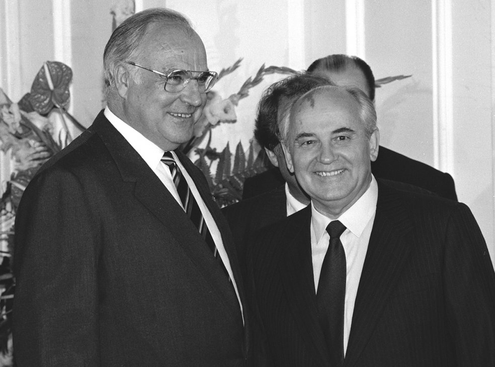 Helmut Kohl steht links neben Michail Gorbatschow, beide lächeln.