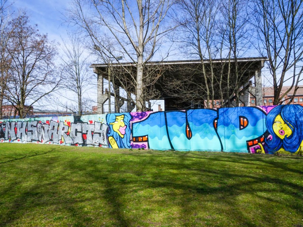 Hinterlandmauer und Lichttrasse der Vorfeldsicherung der DDR-Grenzanlagen an der Puschkinallee in Berlin-Treptow, die nach dem Mauerfall bemalt wurde (2); Aufnahme 2015
