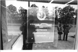 Durch eine Scheibe fotografiertes Schild mit dem Emblem der DDR und der Aufschrift: Ständige Vertretung der Deutschen Demokratischen Republik.