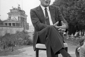 1986: Willy Brandt wird am 25. Jahrestag des Mauerbaus vor der Mauer am Brandenburger Tor von einem amerikanischen Fernsehsender interviewt. Rechts davon befindet sich das Reichstagsgeb&auml;ude, in dem eine offizielle Gedenkveranstaltung stattfindet.