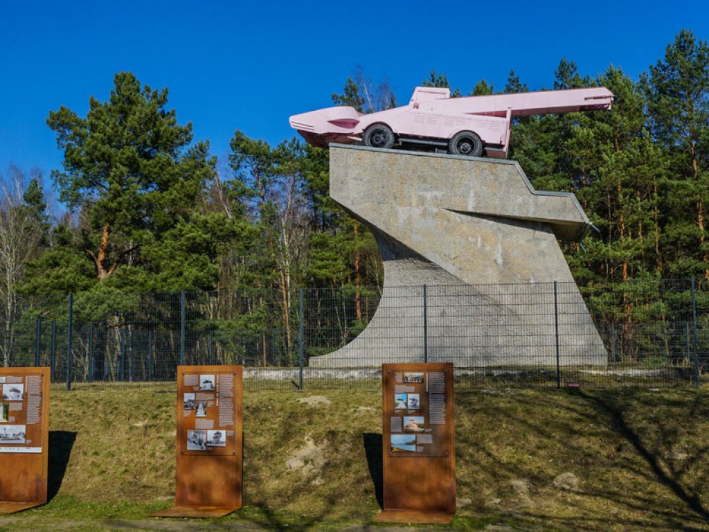 „Panzerdenkmal“: Seit 1992 ziert ein rosa lackierter Schneelader – ein Kunstwerk von Eckhart Haisch – den Ehrenmalsockel am DDR-Grenzübergang Drewitz, auf dem bis dahin ein sowjetischer T34-Panzer das Kanonenrohr auf West-Berlin richtete (1); Aufnahme 2015