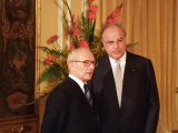 Honecker steht links neben Kohl. Im Hintergrund ein golden gerahmtes Bild und ein großer Blumenstrauß.