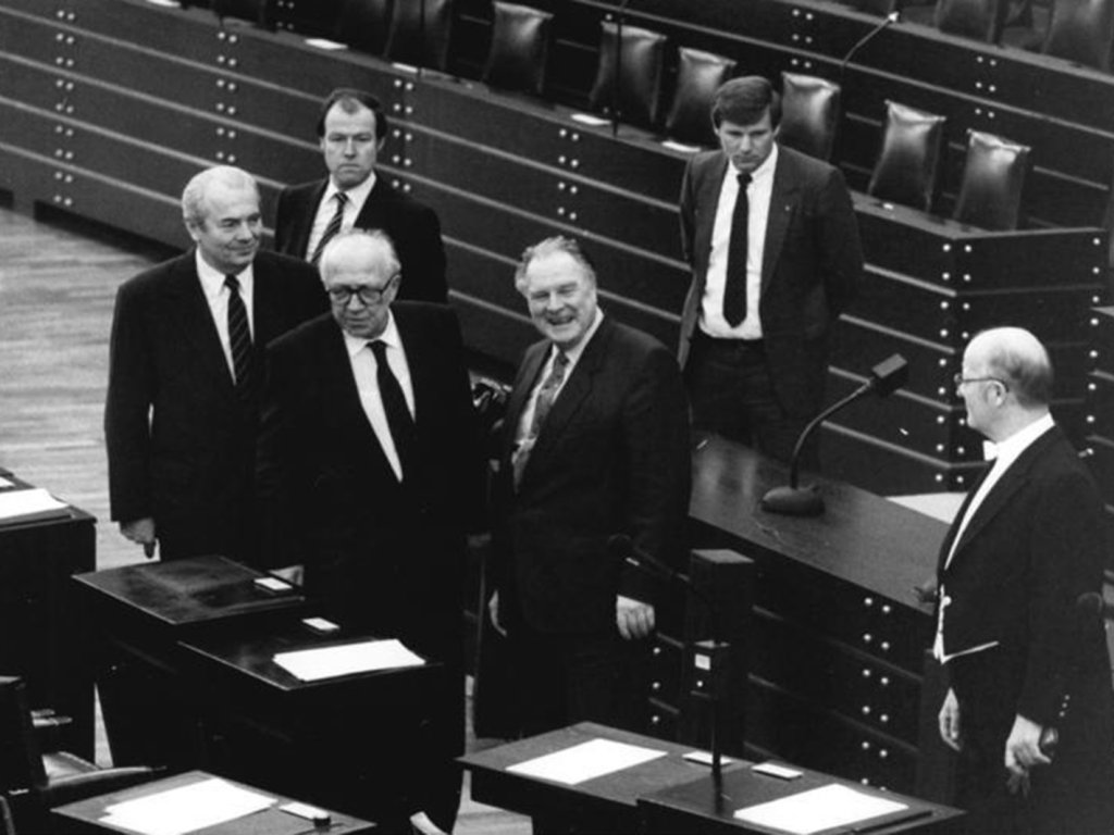 Die drei Männer stehen zwischen Rednerpulten, Westphal lacht in die Kamera. Drei weitere Männer stehen hinter und neben ihnen.