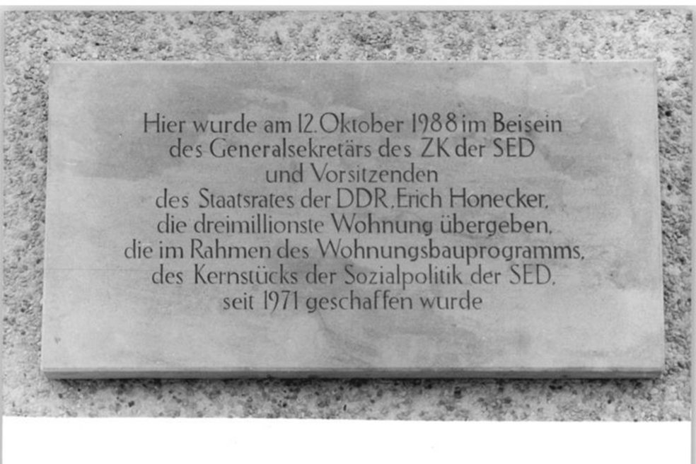 Steinplakette mit der Inschrift: Hier wurde am 12. Oktober 1988 im Beisein des Generalsekret&auml;rs des ZK der SED und Vorsitzenden des Staatsrates der DDR, Erich Honecker, die dreimillionste Wohnung &uuml;bergeben, die im Rahmen des Wohnungsbauprogramms, des Kernst&uuml;cks der Sozialpolitik der SED, seit 1971 geschaffen wurde.