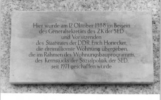 Steinplakette mit der Inschrift: Hier wurde am 12. Oktober 1988 im Beisein des Generalsekretärs des ZK der SED und Vorsitzenden des Staatsrates der DDR, Erich Honecker, die dreimillionste Wohnung übergeben, die im Rahmen des Wohnungsbauprogramms, des Kernstücks der Sozialpolitik der SED, seit 1971 geschaffen wurde.