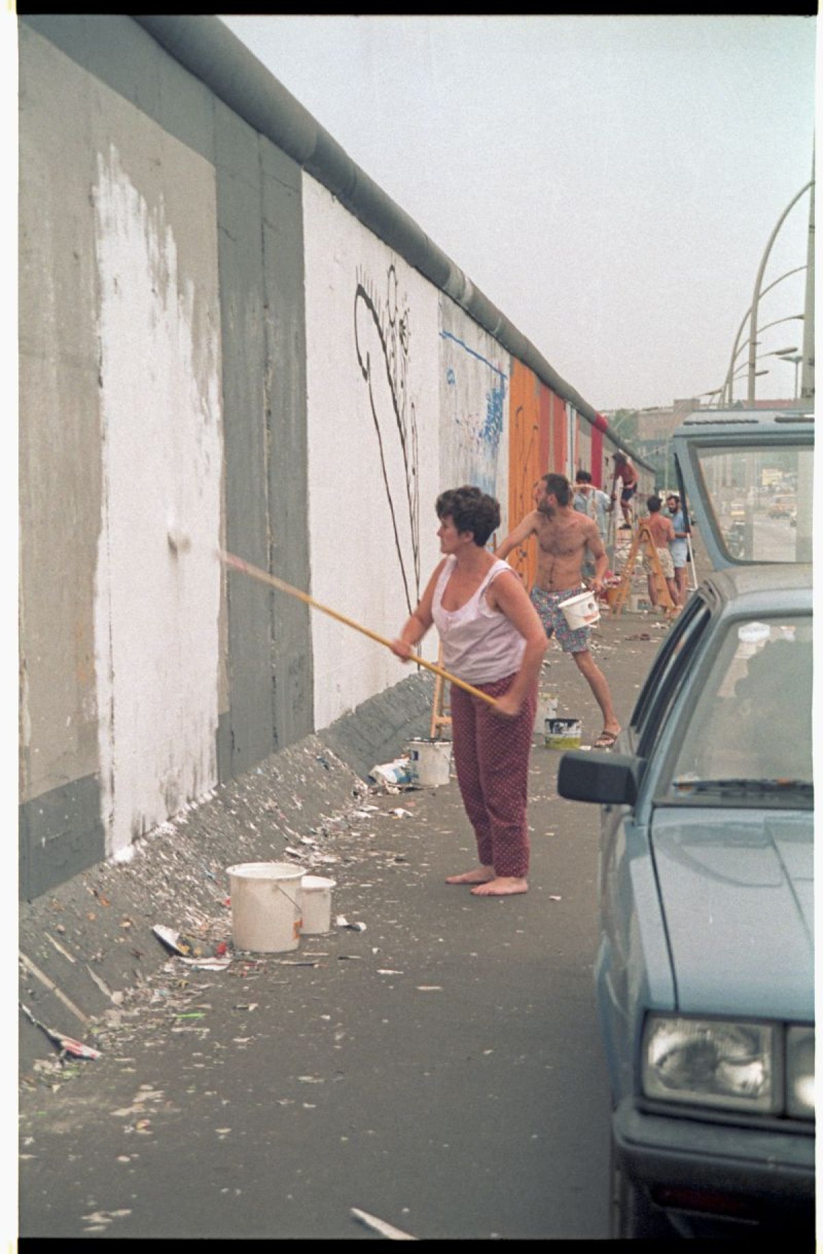 Christine Kühn bereitet mit einer Grundierung das Bild "Touch the Wall" auf der East Side Gallery vor