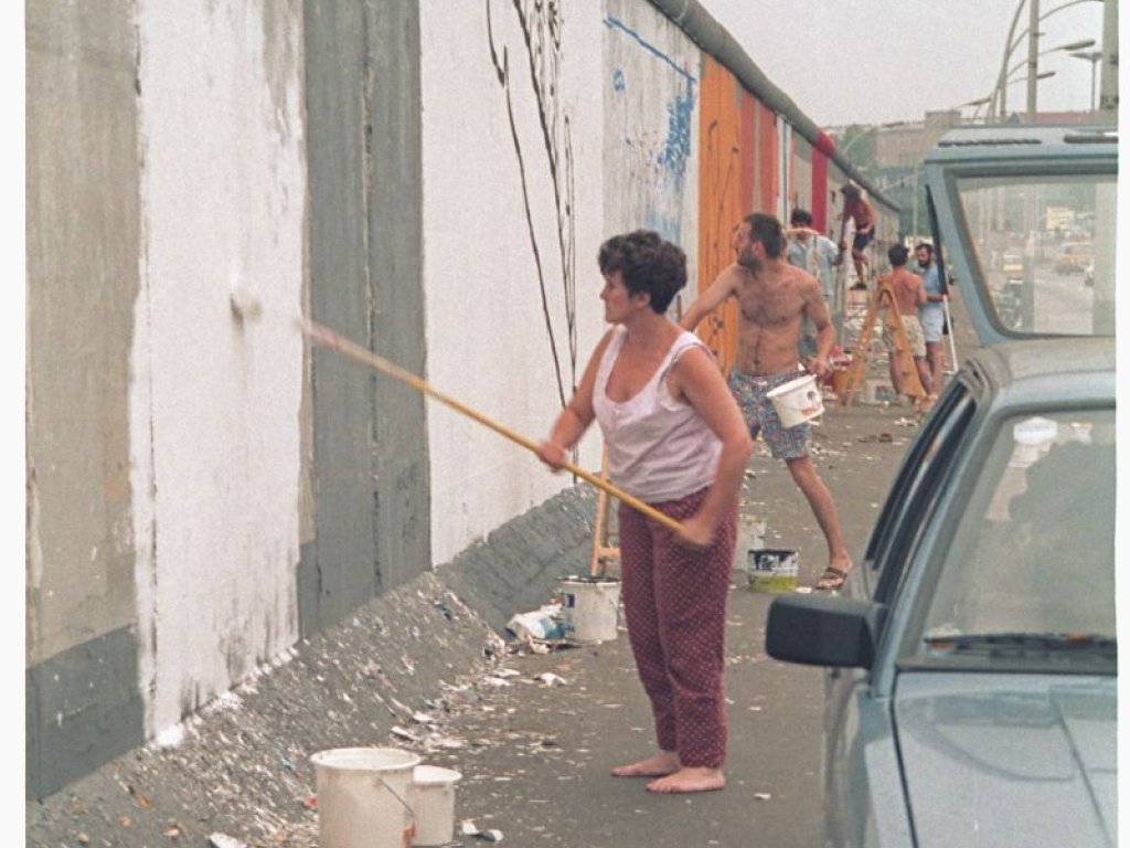 Christine Kühn bereitet mit einer Grundierung das Bild "Touch the Wall" auf der East Side Gallery vor