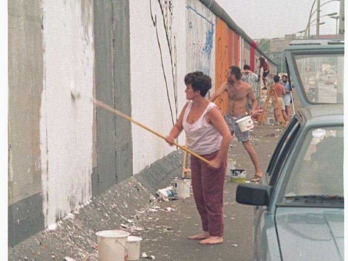 Christine Kühn bereitet mit einer Grundierung das Bild "Touch the Wall" auf der East Side Gallery vor