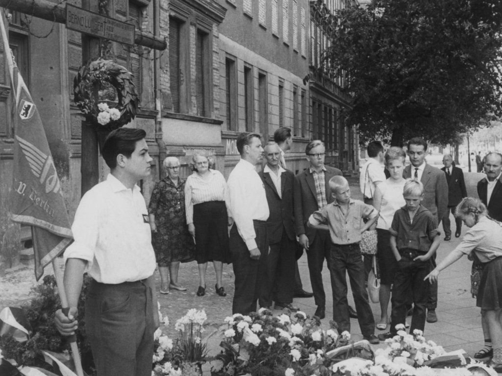 1962: Am Todesort von Bernd Lünser in der Bernauer Straße im Wedding steht am ersten Jahrestag des Mauerbaus die Ehrenwache eines Jugendverbandes.