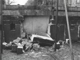 Aus der Hohlblockstein-Mauer sind große Stücke herausgebrochen und liegen auf dem Straßenpflaster davor. Das Loch ist rückseitig mit Platten verschlossen.