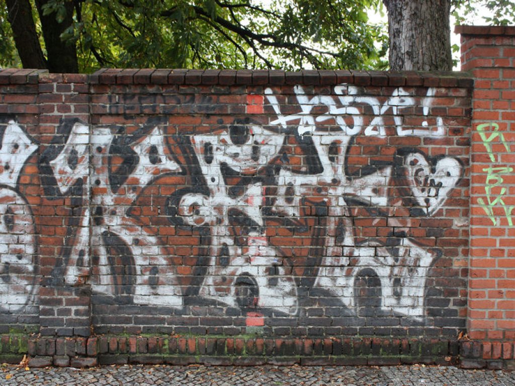 Mit Graffitis übermalte Grenzgebietsmarkierung auf der Friedhofsmauer an der Ackerstraße (in der Bildmitte oben sowie unten); Aufnahme 2016