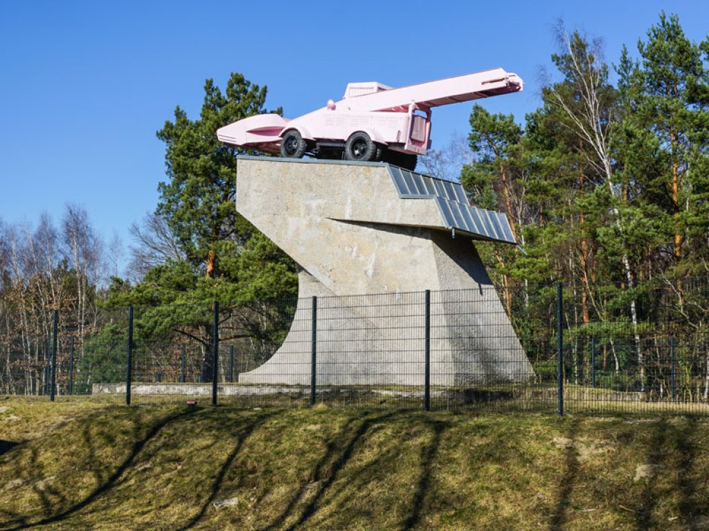 „Panzerdenkmal“: Seit 1992 ziert ein rosa lackierter Schneelader– ein Kunstwerk von Eckhart Haisch – den Ehrenmalsockel am DDR-Grenzübergang Drewitz, auf dem bis dahin ein sowjetischer T34-Panzer das Kanonenrohr auf West-Berlin richtete (2); Aufnahme 2015