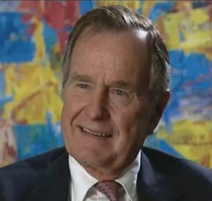 Porträtaufnahme von George Bush, lächelnd vor einem bunten Hintergrund.