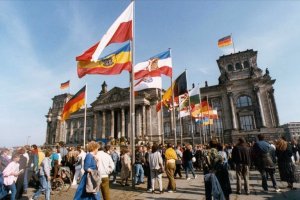 Um die schwarz-rot-goldene Fahne gruppieren sich vor dem Reichstagsgebäude die Fahnen aller Bundesländer Deutschlands, 3. Oktober 1990.