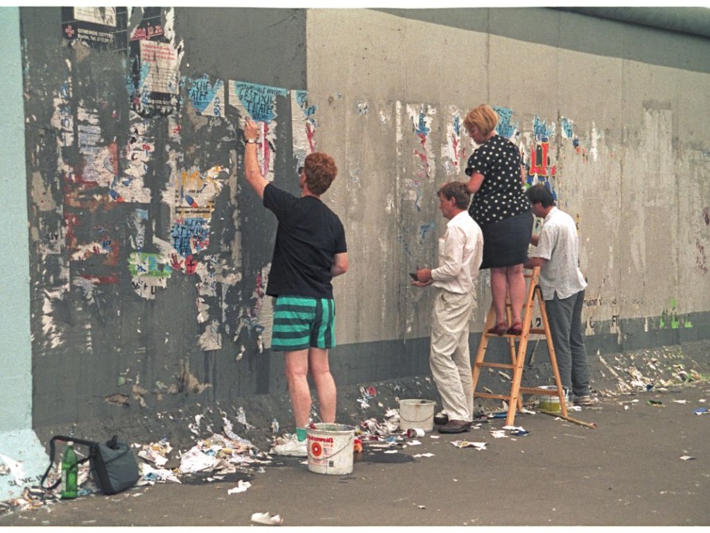 Christine Kühn mit Helfern beim Entfernen von Plakaten in Vorbereitung für Bemalung der Mauer