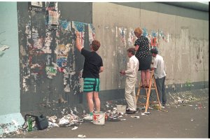 Christine K&uuml;hn mit Helfern beim Entfernen von Plakaten in Vorbereitung f&uuml;r Bemalung der Mauer