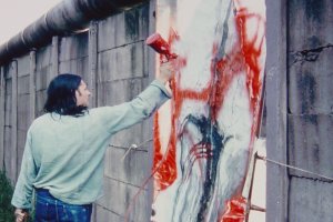 Elsner steht auf einem Haufen herausgebrochener Mauerzeile. Neben ihm in der Mauerl&uuml;cke ist sein abstraktes Bild eingesetzt, das er mit einer Spr&uuml;hpistole mit roter Farbe weiter bearbeitet.