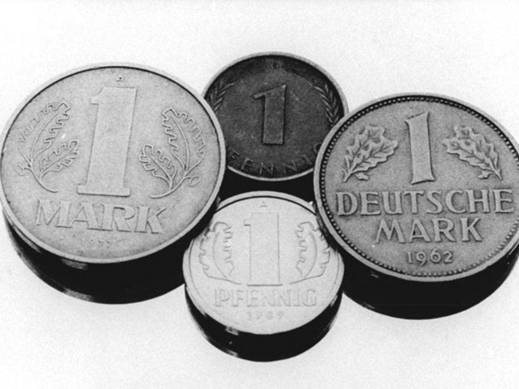 Bundeskanzler Kohl und Ministerratsvorsitzender de Maizière verhandeln über die Währungsunion, die schon im Juli in Kraft treten soll (v. l. n. r.: 1 Mark der DDR, 1 Pfennig Bundesrepublik und DDR, 1 Deutsche Mark); Aufnahme 24. April 1990