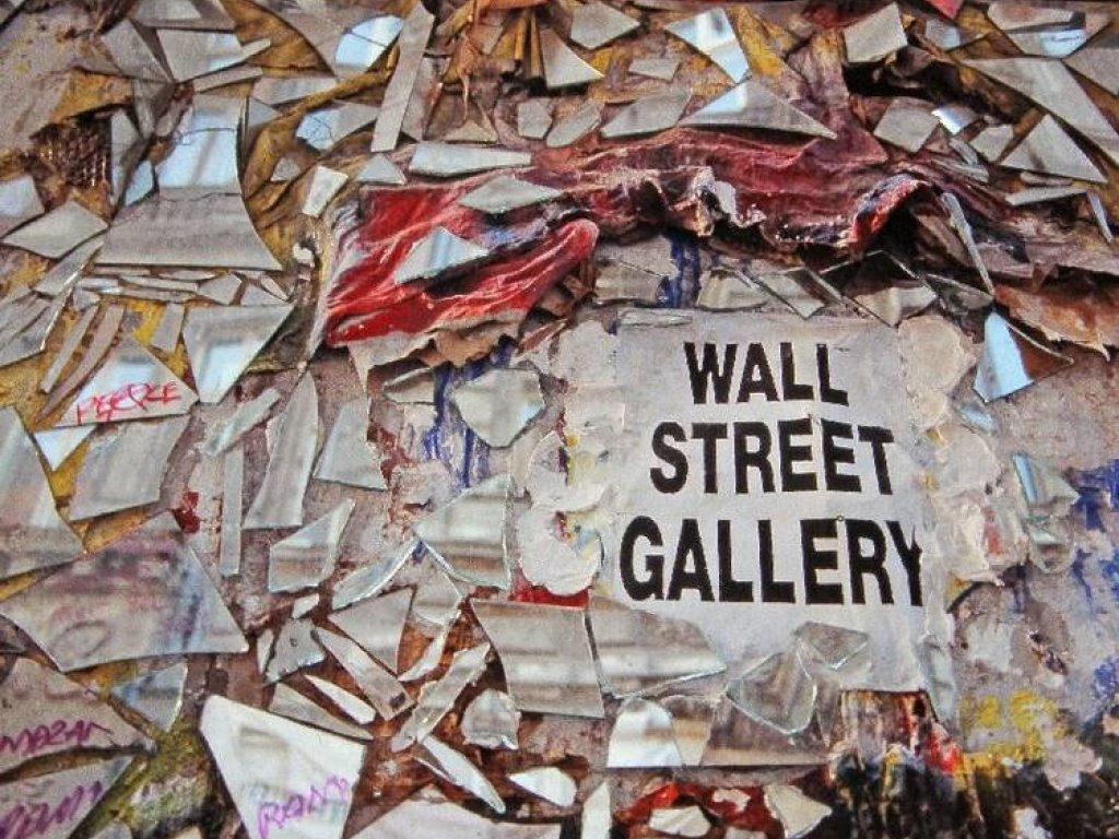 Nahaufnahme von der mit Spiegelsplittern beklebten Mauer. Groß im Bild ist die Aufschrift zu lesen: Wall Street Gallery.
