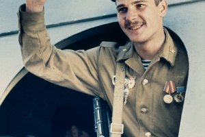 Ein sowjetischer Soldat steht lächelnd in der Tür eines Flugzeuges und hebt die rechte Hand zum Gruß.