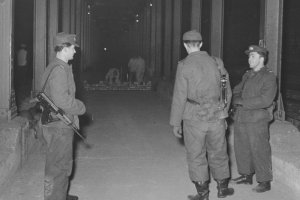 Grenzsoldaten bewachen Maurer, die eine Sperrmauer zwischen den Berliner U-Bahnhöfen Heinrich-Heine-Straße und Moritzplatz errichten, 15. Februar 1963.